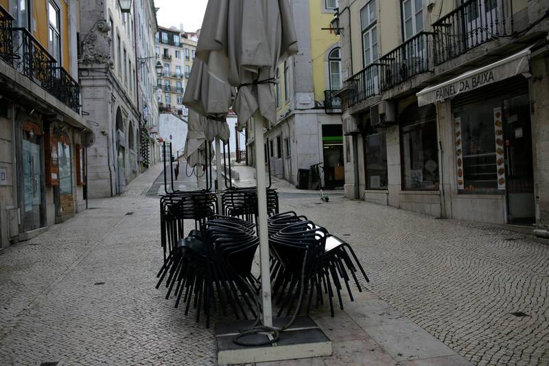 Tables and chairs from a closed restaurant terrace are piled in a deserted pedestrian street in Lisbon.  AP Photo