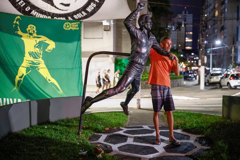 A man touches a statue depicting Brazilian football legend Pele in Santos. Reuters