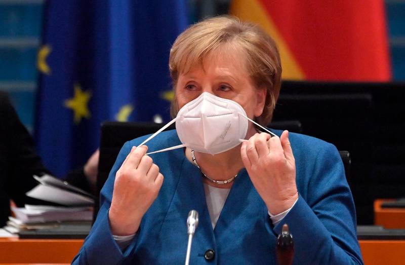 German Chancellor Angela Merkel takes off her face mask as she prepares to lead the weekly cabinet meeting at the Chancellery in Berlin. AFP