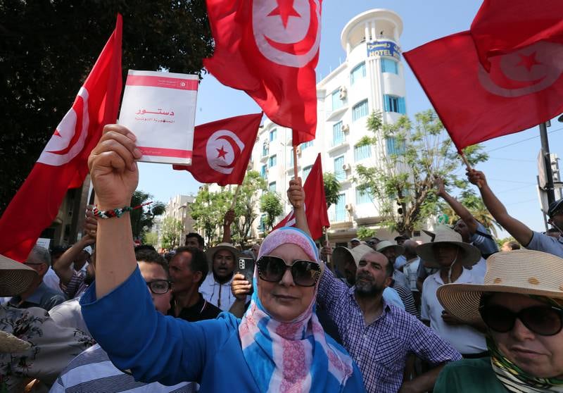 A woman holds up the Tunisian constitution during a protest against Mr Saied and his call for a constitutional referendum. EPA