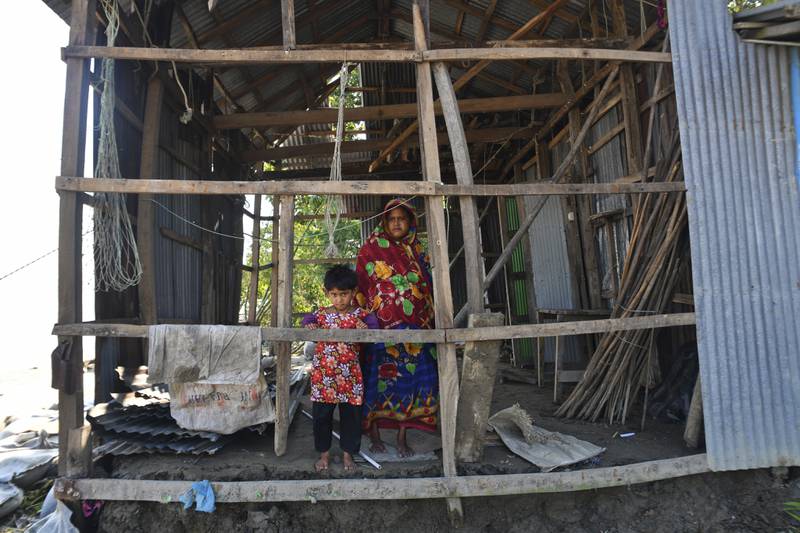 A Bangladeshi woman and a child survey their damaged house after Sitrang lashed the Bay of Bengal coast in Char Fasson, Bhola district. AP Photo