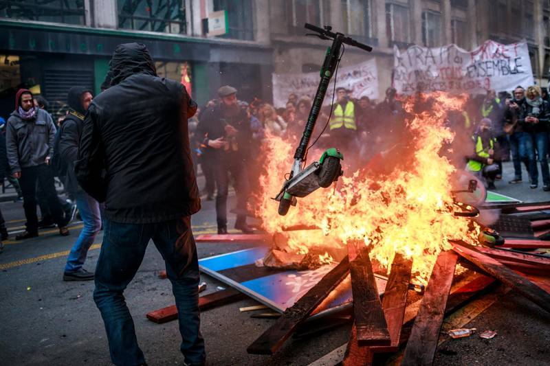 'Gilets Jaunes' (Yellow Vest) protesters throw scooters into a burning fire barricade during a demonstration against pension reforms lead by French Unions in Paris, France.  EPA