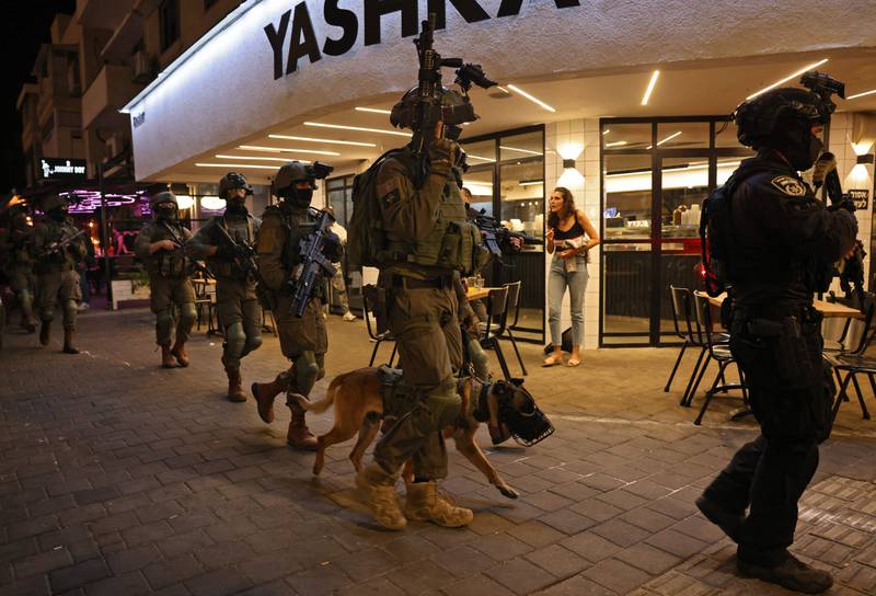 A security forces' member with a police dog walks outside a restaurant at the scene of a shooting attack in Dizengoff Street in the centre of Israel's Mediterranean coastal city of Tel Aviv on April 7, 2022.  AFP
