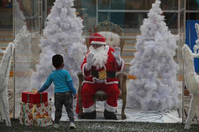 Dressed as Santa Claus, David Pizarro talks to a boy from inside a plastic enclosure in an effort to curb the spread of Covid-19, at a square in the Comas municipality of Lima, Peru. AP Photo