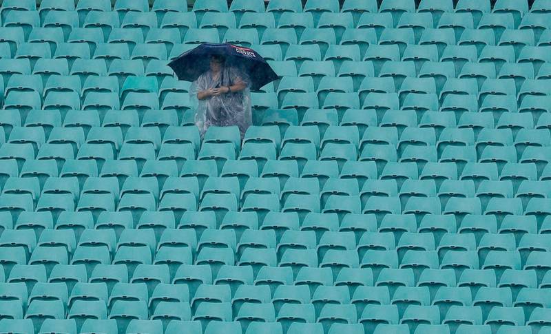 A solitary fan huddles under an umbrella as rain falls on the Sydney Cricket Ground delaying the start of the Women's T20 World Cup cricket semi-final matches in Sydney, on Thursday, March 5. AP