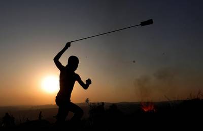 A Palestinian demonstrator uses a sling to hurl stones at Israeli troops during a protest against Israeli land seizures for Jewish settlements, in the village of Ras Karkar, near Ramallah in the occupied West Bank September 4, 2018. REUTERS/Mohamad Torokman