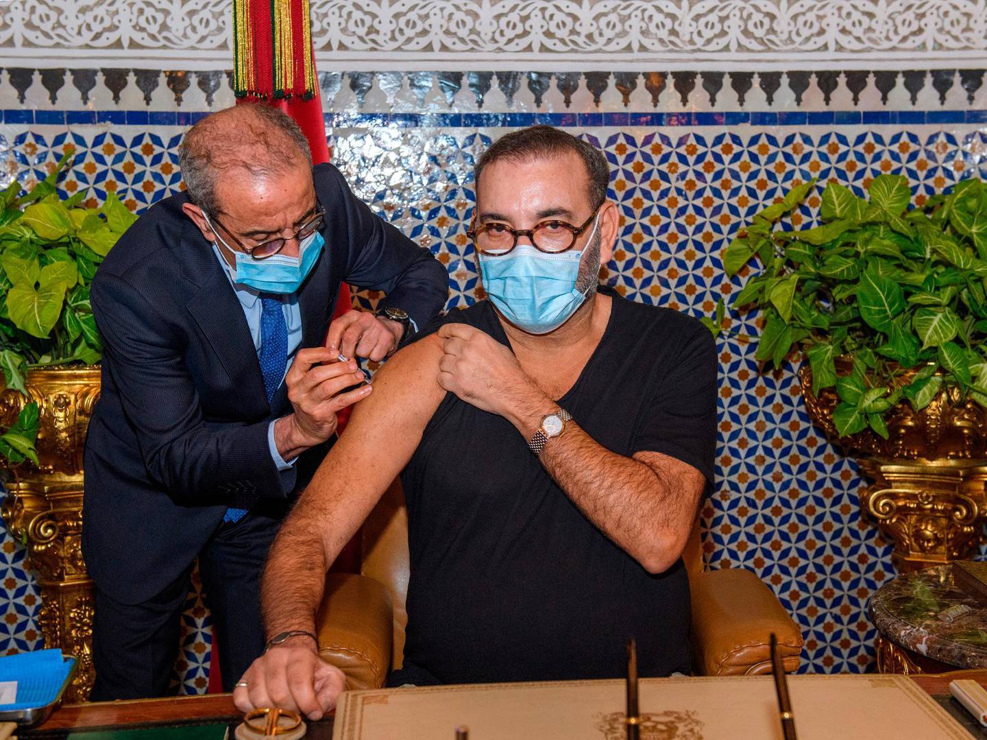 In this photo released by the Royal Palace, Morocco's King Mohammed VI, right, receives the COVID-19 vaccine at the Royal Palace in Fes, as he launches his country's coronavirus vaccination campaign, Thursday Jan. 28, 2021. The North African kingdom received its first shipments of vaccine doses in recent days from China's Sinopharm and Anglo-Swedish drug maker AstraZeneca. (Moroccan Royal Palace via AP)