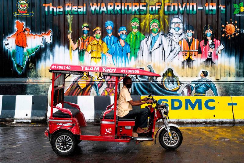 An electic-rickshaw drier rides past a mural painted on a garbage dump after the government eased a nationwide lockdown imposed as a preventive measure against the coronavirus in New Delhi.   AFP