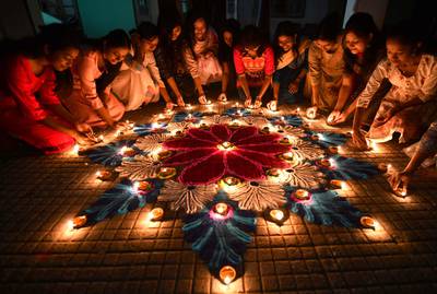Students light earthen oil lamps on rangoli, a decorative design, on the occasion of the Diwali, a Hindu festival of lights in Guwahati on November 12, 2023.  (Photo by Biju BORO  /  AFP)