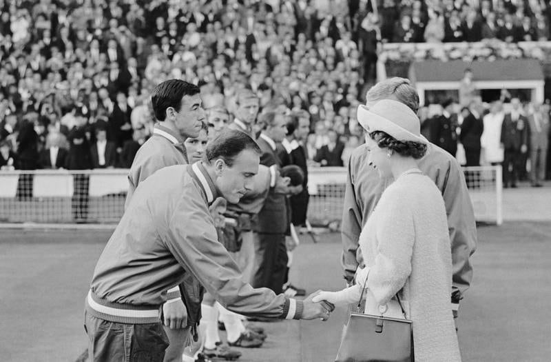 Queen Elizabeth II shaking hands with footballer George Cohen at Wembley before England's first group game of the 1966 World Cup. Gordon Banks stands next to Cohen. Getty