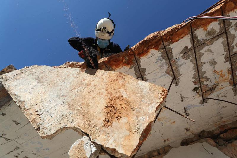 A member of the Syrian Civil Defence, or White Helmets, cuts off a slab of concrete hanging from the roof of a building damaged during bombing by pro-government forces in Idlib province. AFP