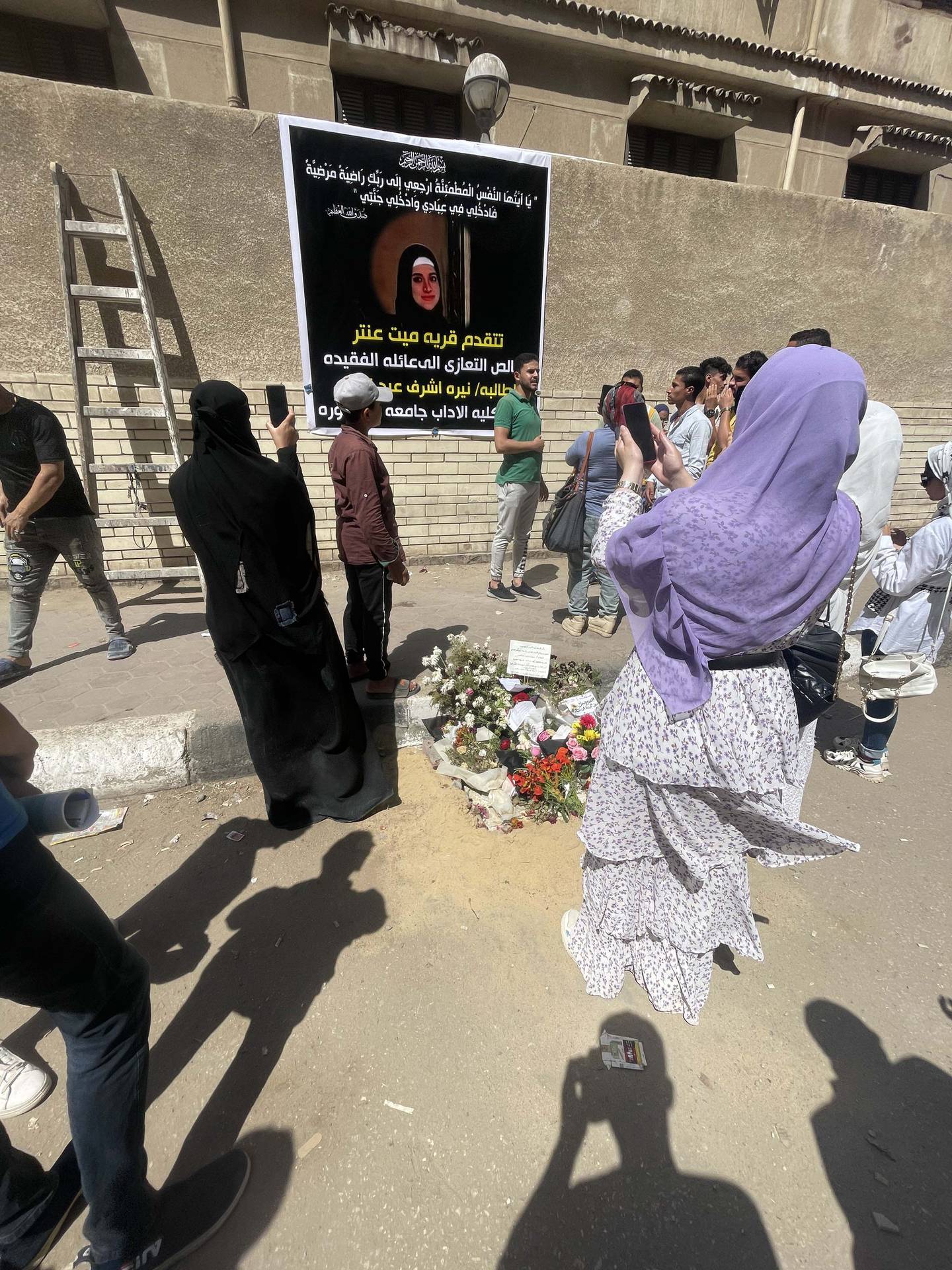 Residents of the Egyptian city of Mansoura view a poster in memory of 21-year-old literature student Nayera Ashraf who was murdered outside the university gate on Monday, June 20. Kamal Tabikha / The National