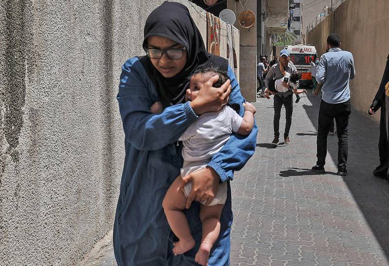 A woman cradles a child as Palestinians evacuate a building targeted by an Israeli bombardment in Gaza City. AFP