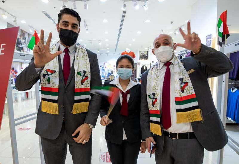 Employees at Al Wahda Mall in Abu Dhabi show off their UAE scarves for National Day. Victor Besa / The National