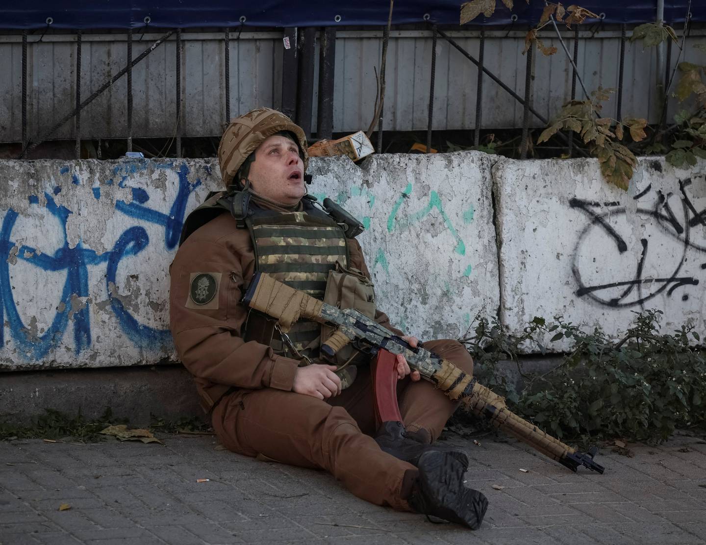 A Ukrainian serviceman takes cover as an air raid siren sounds during a Russian drone strike in Kyiv. Reuters