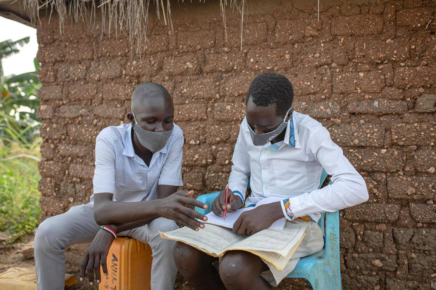Jonathan*, 15 helping Peter, 15* to study. The boys are friends living in a refugee settlement for South Sudanese refugees in West Nile, Uganda. Jonathan inspired Peter, to go back to school after he had stopped attending school and had started working as a tailor. As friends, they spend time chatting, playing football, and studying.