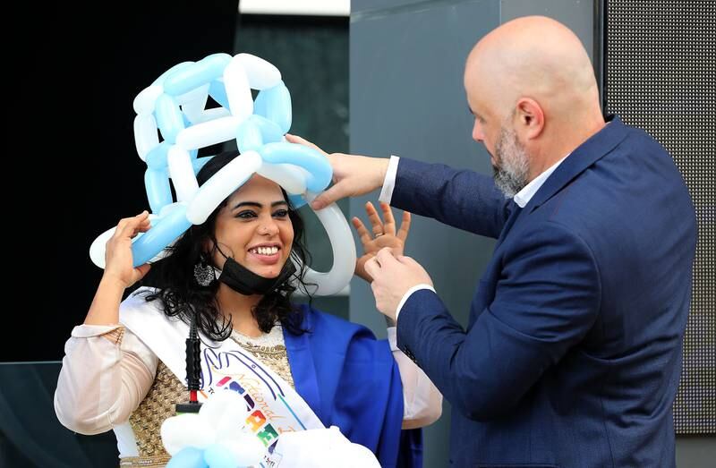 A visitor wears a hat made from blue and white balloons.