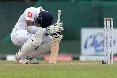 Sri Lankan cricket team captain Dimuth Karunaratne reacts after been hit by the ball during the final day of the final cricket Test match between Sri Lanka and New Zealand at P. Sara Oval cricket stadium in Colombo on August 26, 2019. / AFP / LAKRUWAN WANNIARACHCHI
