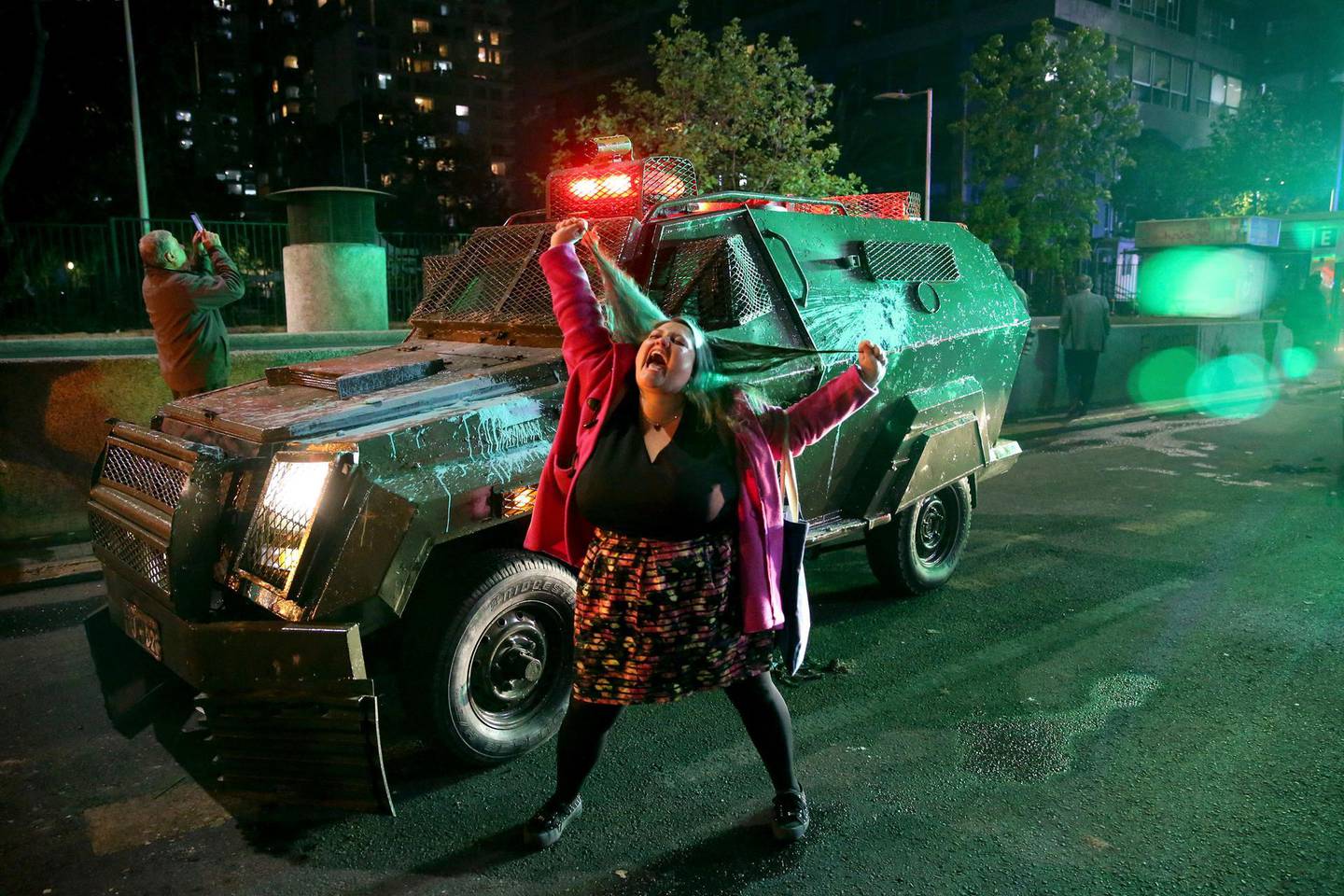 A woman shouts in front of a police truck near the Santa Lucia subway station during a protest against the rising cost of subway and bus fares, in Santiago, Friday, Oct. 18, 2019. (AP Photo/Esteban Felix)