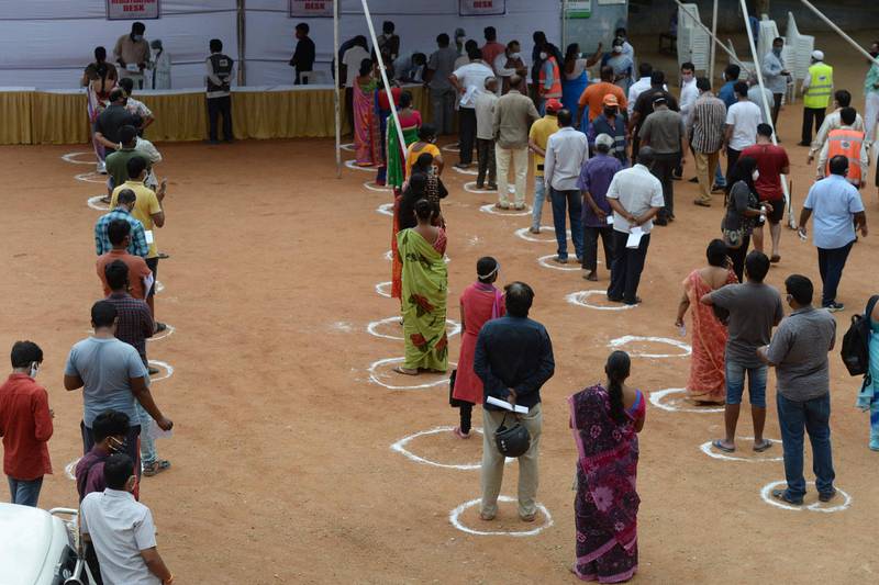 Circles on the ground delimit physical distancing as people wait to register for a special vaccination programme against Covid-19 at a government school in Hyderabad. AFP