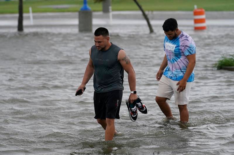 Jesse Perez and Sergio Hijuelo walk through flooded streets near Lake Pontchartrain. AP