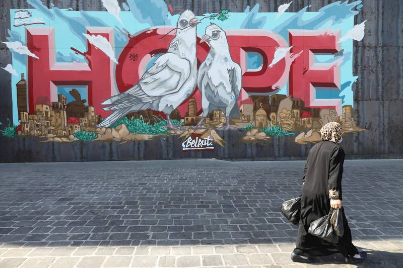 People walk past a "Hope" graffiti painted on a fenced off entrance of a hotel in Beirut, Lebanon. Getty Images