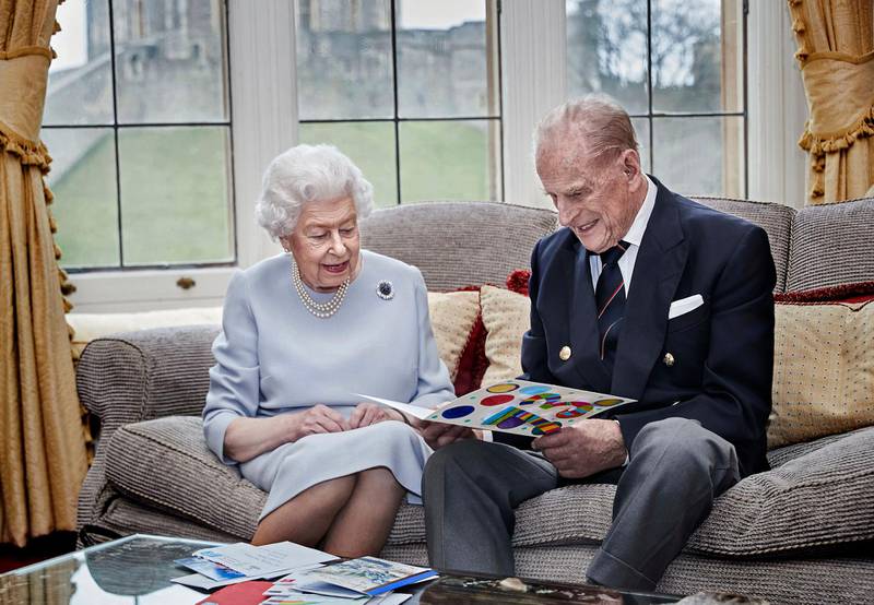 Queen Elizabeth II and Prince Philip, Duke of Edinburgh look at their homemade wedding anniversary card, given to them by their great grandchildren Prince George, Princess Charlotte and Prince Louis, in the Oak Room at Windsor Castle ahead of their 73rd wedding anniversary. Getty Images