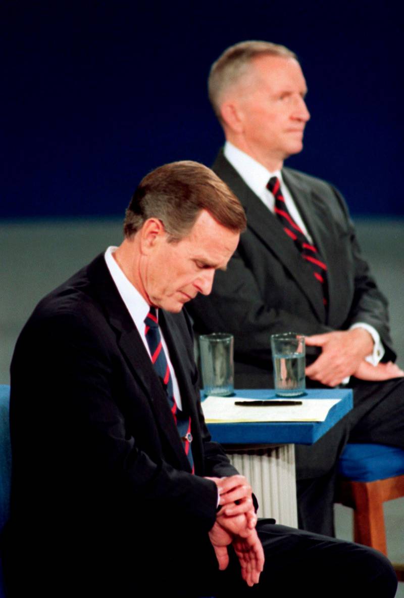 FILE - In this Oct. 15, 1992, file photo President George H.W. Bush looks at his watch during the 1992 presidential campaign debate with other candidates, Independent Ross Perot, top, and Democrat Bill Clinton, not shown, at the University of Richmond, Va. They spend hours mastering policy. Learning to lean on the podium just so. Perfecting the best way to label their opponents as liars without whining. But presidential candidates and their running mates often find that campaign debates turn on unplanned zingers, gaffes or gestures that speak volumes. Debate wins and losses often are scored based on the overall impressions that candidates leave with voters. In the history books, though, small debate moments often end up telling the broader story. (AP Photo/Ron Edmonds, File)
