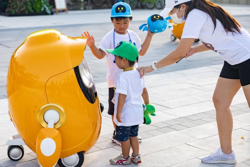 Children interacting with one of the Opti robots at Expo 2020 Dubai.