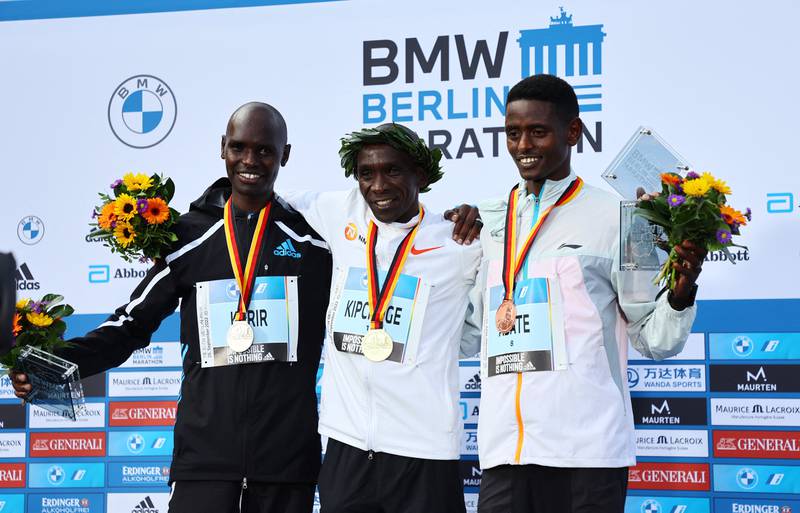 Eliud Kipchoge celebrates on the podium alongside runner-up Mark Korir and third-placed Tadu Abate after winning the Berlin Marathon. Reuters