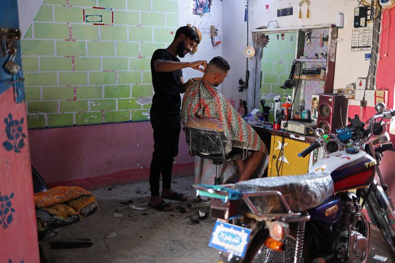 Abdul Abbas Ali, 24, works in his barber shop next to his family home, in the village of Al-Bu Hussain which sits on the bank of a former canal which has dried up, in Diwaniya, Iraq