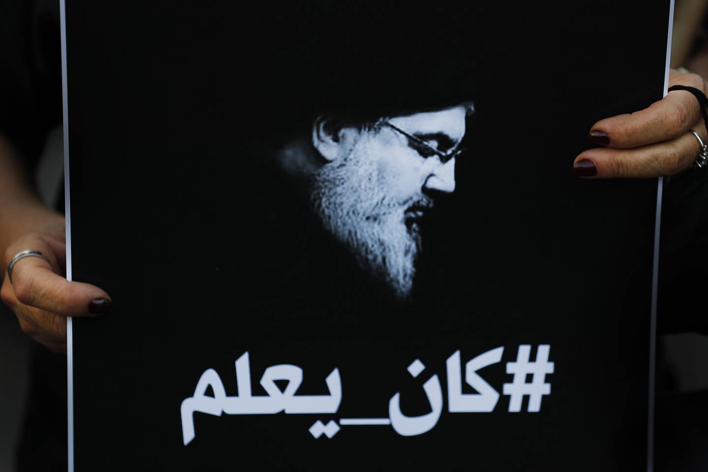 A Lebanese protester holds a portrait of Hezbollah leader Hassan Nasrallah with Arabic that reads, "He knew," referring to the thousand tonnes of ammonium nitrates that exploded at Beirut seaport, during a protest against the Hezbollah group and the visit of the Iranian foreign minister, in Beirut, on October 6, 2021. AP