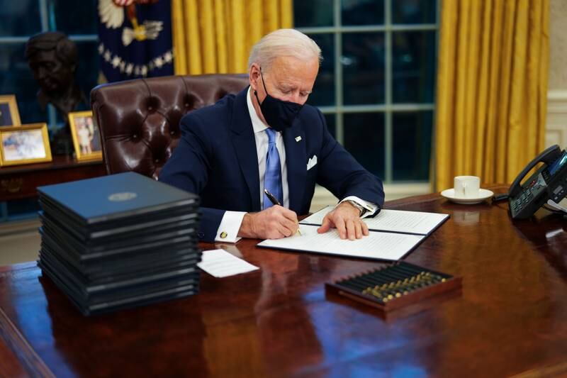 US President Joe Biden signs an executive order on Covid-19 during his first minutes in the Oval Office. EPA