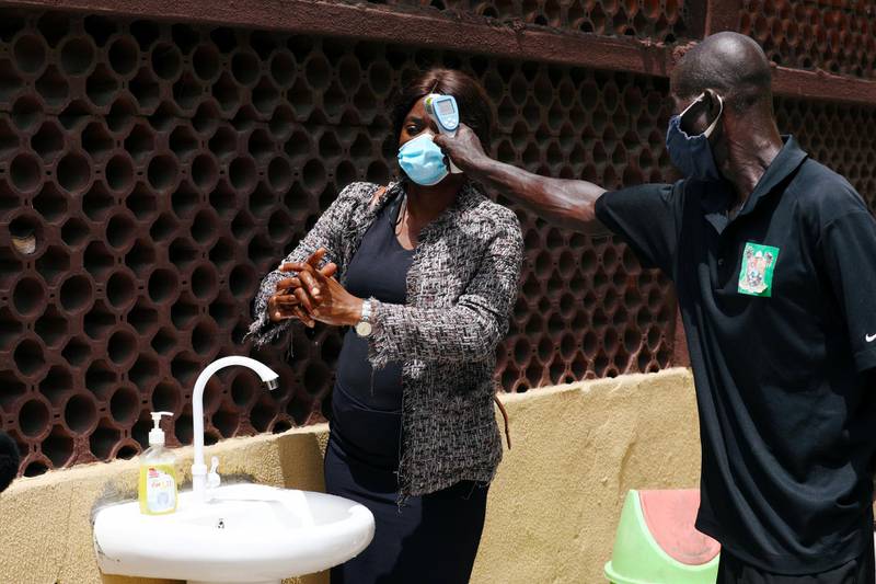 A security staff uses a thermal scanner to check a temperature of a member of the contact-tracing team, at the Primary Healthcare Centre, amid the spread of Covid-19 in Lagos. Reuters