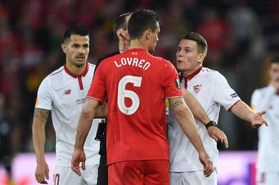 Liverpool’s Croatian defender Dejan Lovren, centre, talks to Sevilla’s French forward Kevin Gameiro, right, after receiving a yellow card. Paul Ellis / AFP