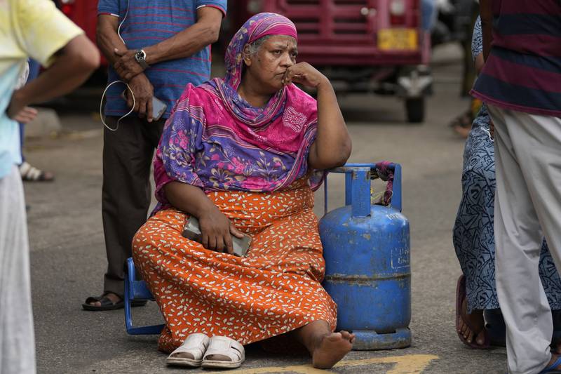 A woman sits outside a police station during a protest in Colombo to demand cooking gas. AP
