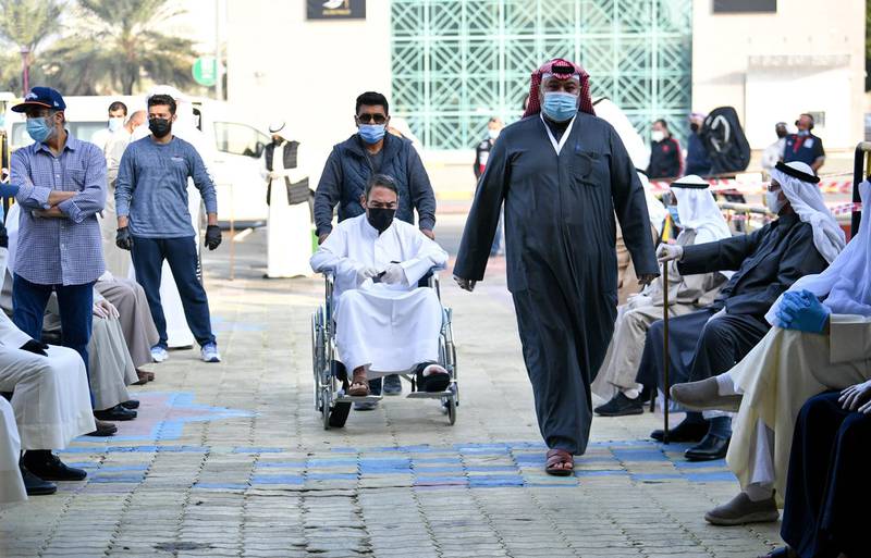 People wearing protective masks arrive to cast their votes at a polling station in Kuwait City. EPA