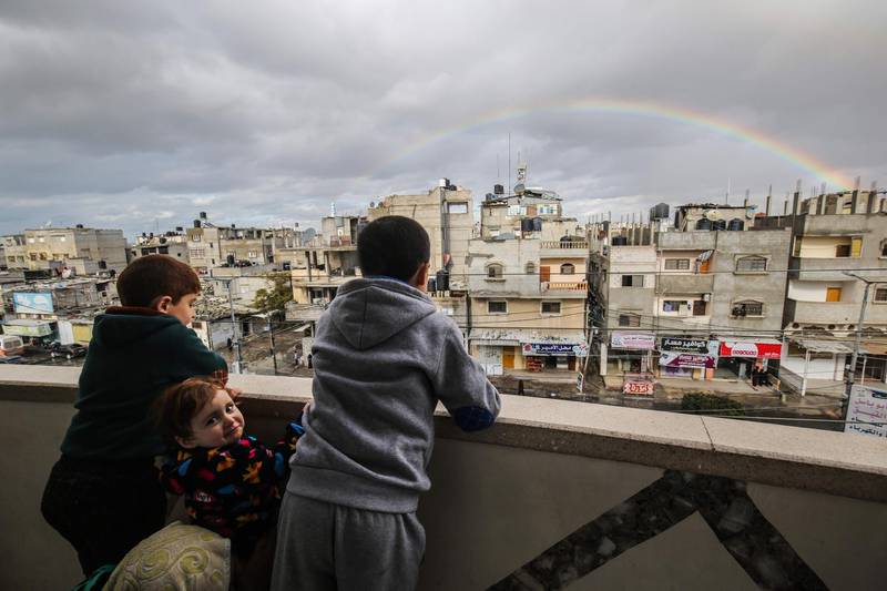 Children look at a rainbow in the sky above Rafah on a rainy day at sunset in the southern Gaza Strip.  AFP