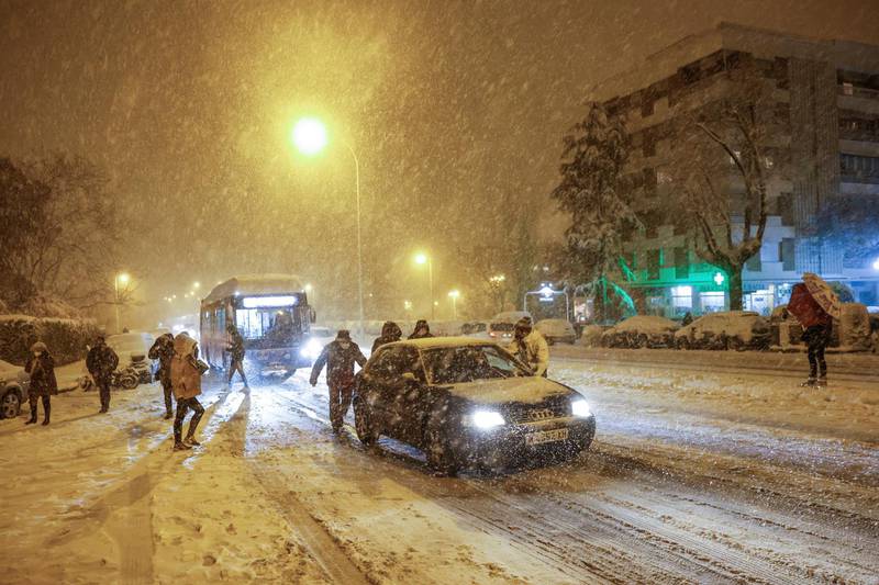 People push a car stranded in the snow in Madrid, Spain.  EPA