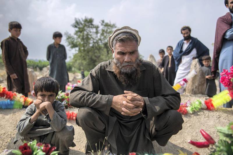Rahat Gul, 45, together with his grandson Lal Agha, 8, sit in front of their grave of Khyber; father to Lal Agha and son to Rahat Gul. A US drone strike meant to target an IS-stronghold accidentally targeted a group of pine nut farmers. 