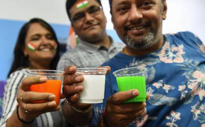Friends pose for souvenir pictures with coloured drinks representing the Indian national flag as they celebrate in Ahmedabad. AFP