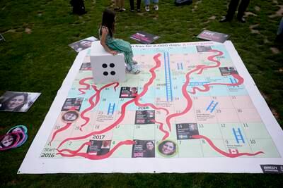 Gabriella sits on the giant snakes and ladders board in Parliament Square. AP