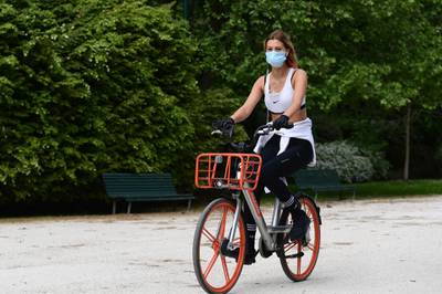 A woman rides a rental bicycle across the Parco Sempione park in Milan. AFP