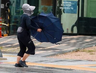 A woman struggles to hold on to her umbrella in strong winds brought by the powerful typhoon in Busan, South Korea. EPA 