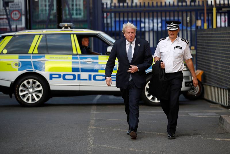 Mr Johnson with Stephen House, acting commissioner of the Metropolitan Police service, during a visit to a police station in London. Getty Images