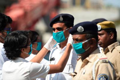 A student adjusts a free facemask to a policeman during a facemaks donation campaing in Ahmedabad.    AFP