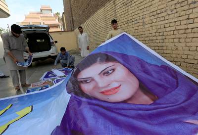 Supporters of parliamentary election candidate Dewa Niazai prepare to install a poster of hers in Jalalabad. Reuters