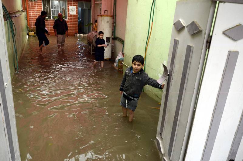 An Iraqi man stands with his sons at his flooded house in Mosul, northern Iraq, on December 1, 2018.  EPA