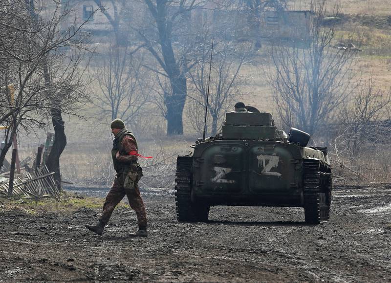A pro-Russian soldier in a uniform without insignia walks next to an armoured vehicle with "Z" painted on its side in the separatist-controlled village of Bugas, Ukraine. Reuters