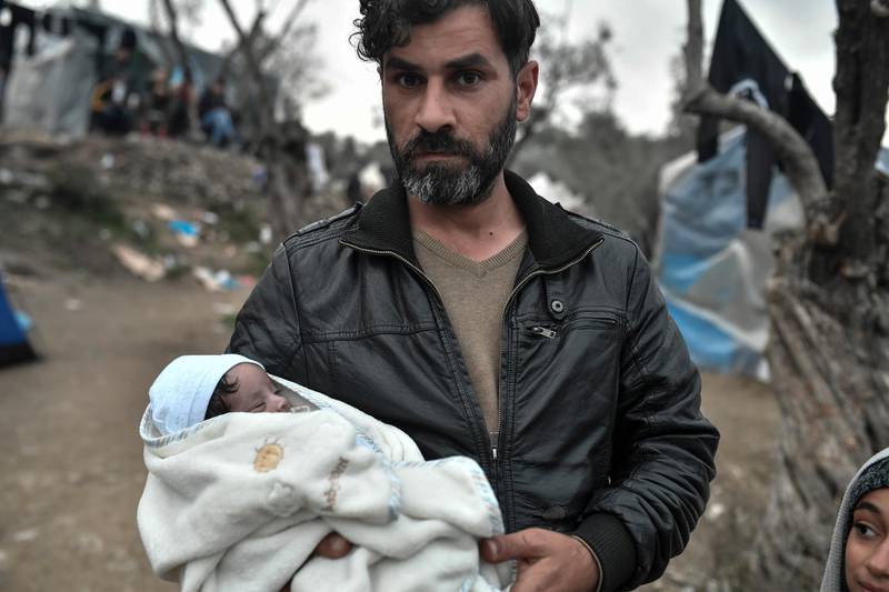 An Iraqi refugee holds his newborn in the overcrowded Moria camp on the island of Lesbos on March 7, 2020. - Over 1,700 migrants have landed on Lesbos and four other Aegean islands from Turkey over the past week, adding to the 38,000 already crammed into abysmal and overstretched refugee centres. (Photo by LOUISA GOULIAMAKI / AFP)